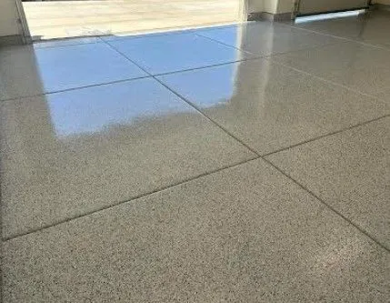 Glossy gray flake epoxy garage floor with saw-cut joints reflecting daylight from the open door.